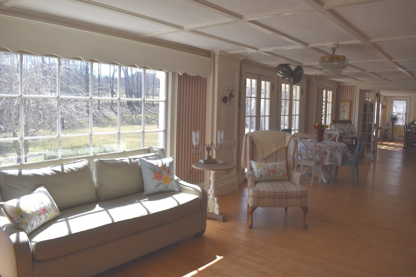 A long sun room with a wall of windows looking out over the fields behind the Inn.
